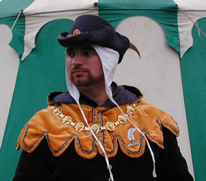 C14th Black Silk Cap, trimmed with Gold Braid and centre front Escutcheon, with a Pheasant feather
